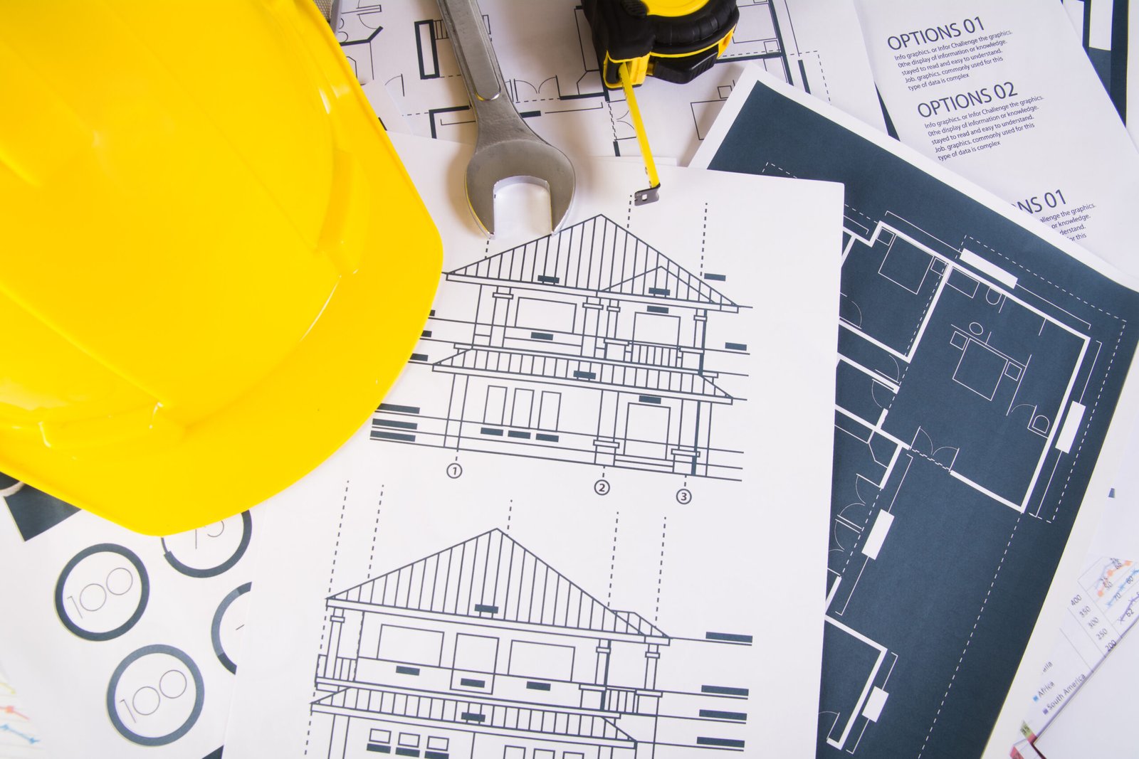 Engineer workplace with blueprints, protractor and safety helmet.
